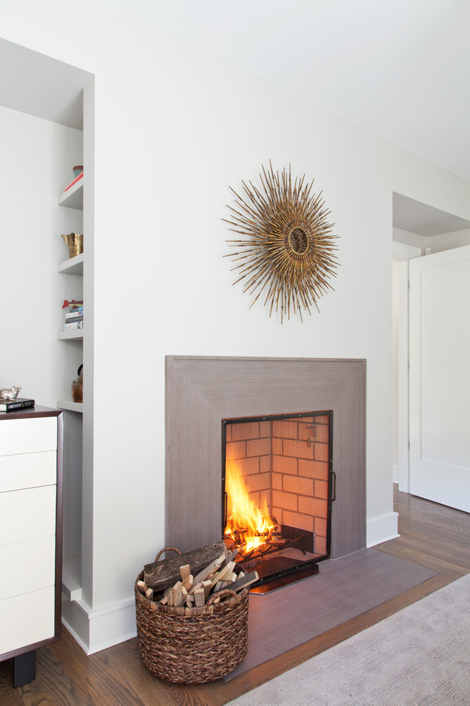 This is an example of a contemporary living room in New York with white walls, dark hardwood floors and a standard fireplace.