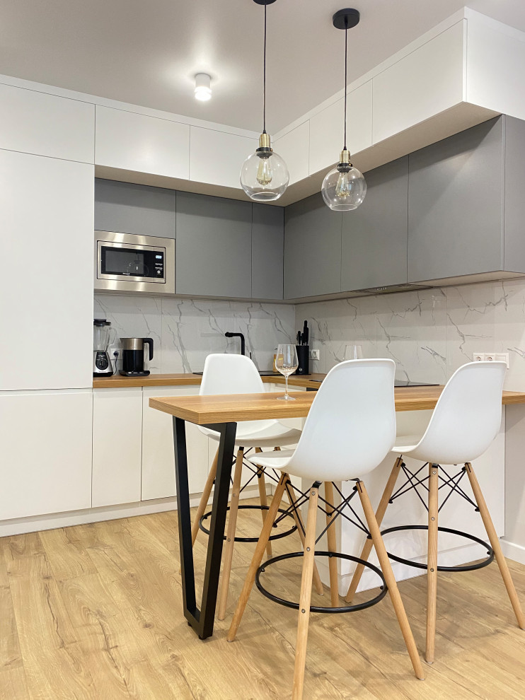 This is an example of a mid-sized scandinavian l-shaped eat-in kitchen in Moscow with flat-panel cabinets, white cabinets, white splashback, with island, brown floor and brown benchtop.