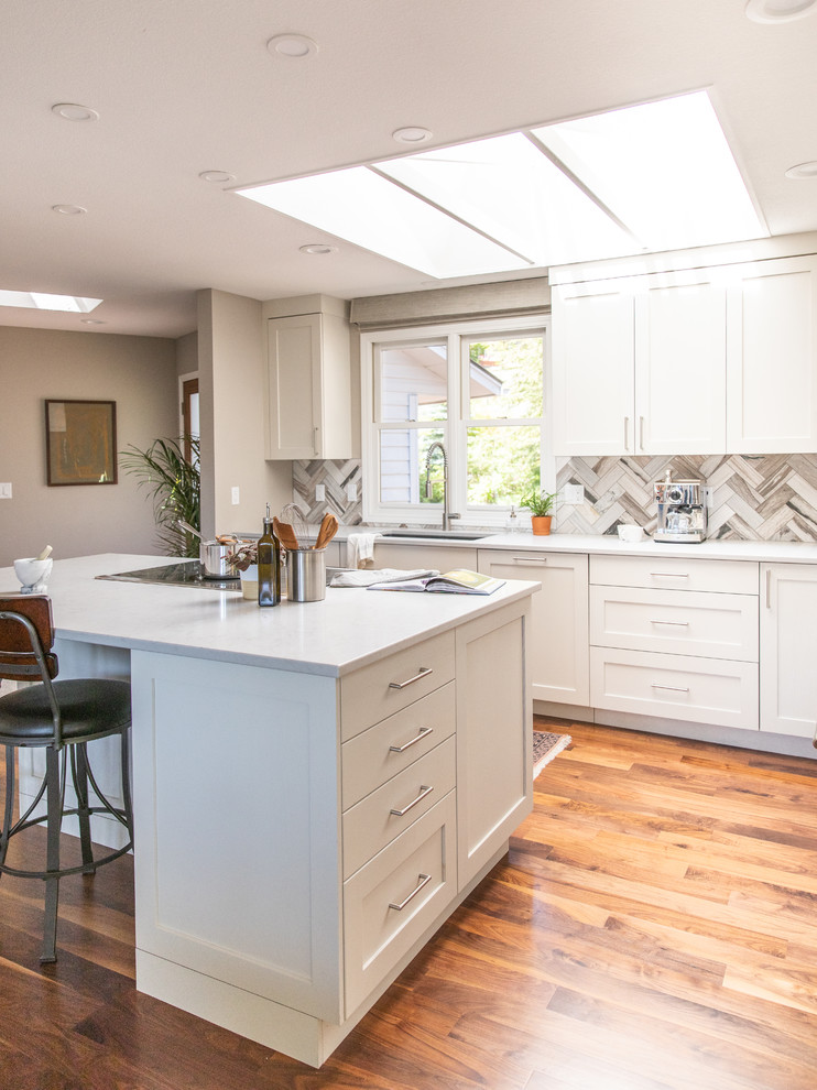 Large contemporary l-shaped eat-in kitchen in Seattle with an undermount sink, shaker cabinets, white cabinets, quartz benchtops, multi-coloured splashback, marble splashback, stainless steel appliances, dark hardwood floors, with island, brown floor and white benchtop.