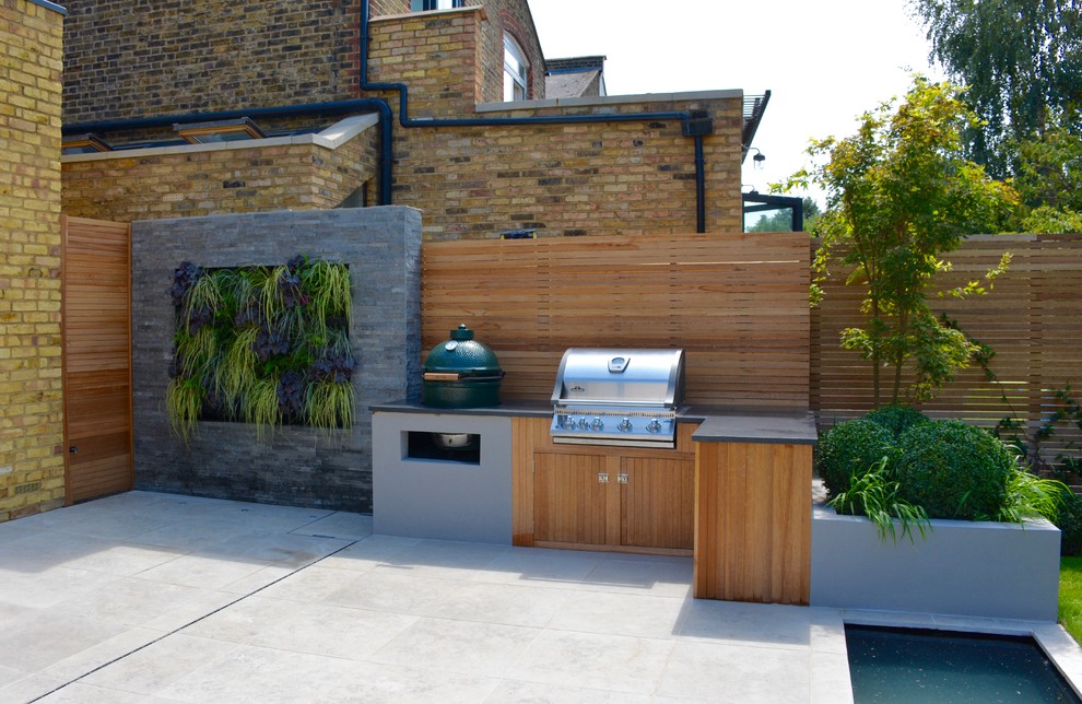 This is an example of a mid-sized contemporary backyard full sun garden for summer in London with with pond and natural stone pavers.