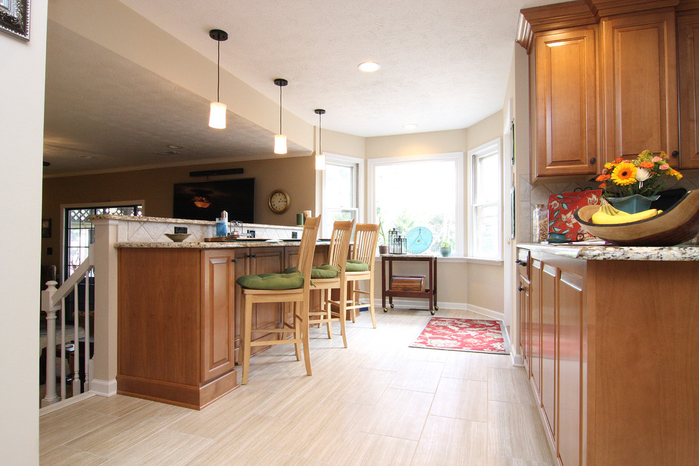 Mid-sized transitional u-shaped porcelain tile eat-in kitchen photo with an undermount sink, raised-panel cabinets, medium tone wood cabinets, granite countertops, beige backsplash, porcelain backsplash and stainless steel appliances