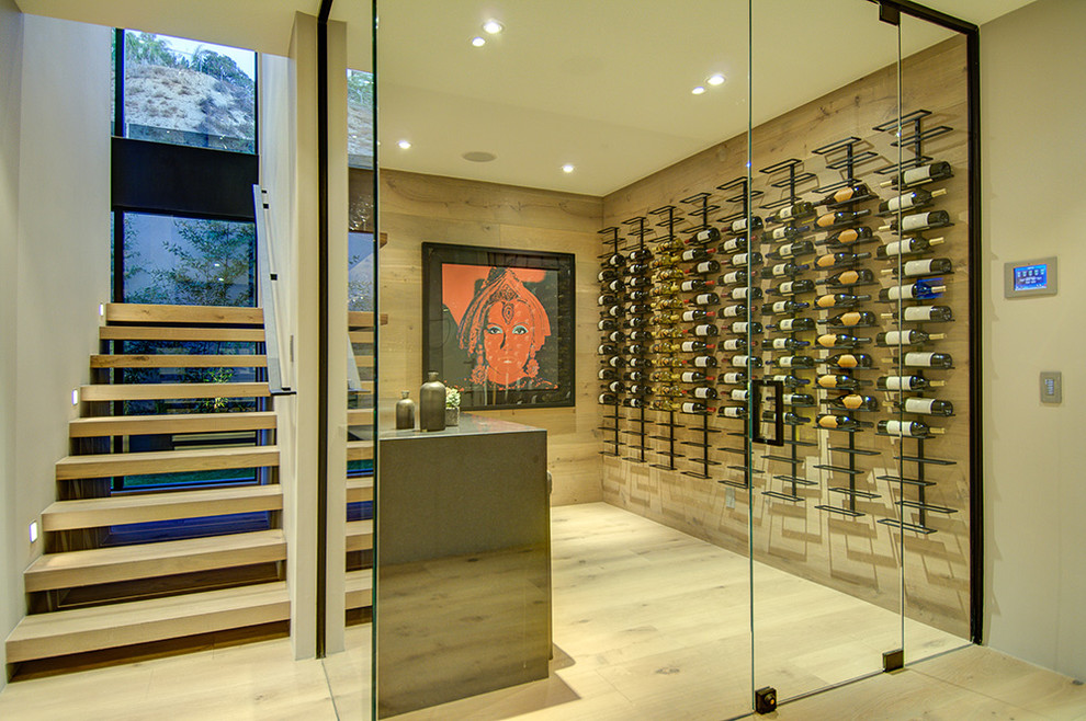 Photo of a modern wine cellar in Los Angeles with light hardwood floors, display racks and white floor.