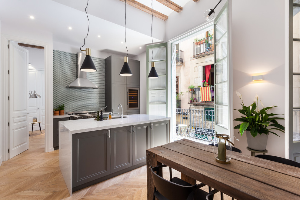 Photo of a mid-sized contemporary single-wall open plan kitchen in Barcelona with recessed-panel cabinets, grey cabinets, marble benchtops, multi-coloured splashback, mosaic tile splashback, medium hardwood floors, with island and beige floor.