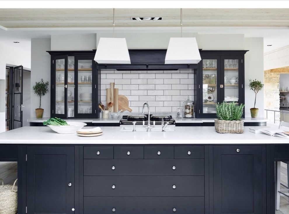 Large country galley kitchen in Berlin with shaker cabinets, white splashback, subway tile splashback, with island, a drop-in sink and blue cabinets.