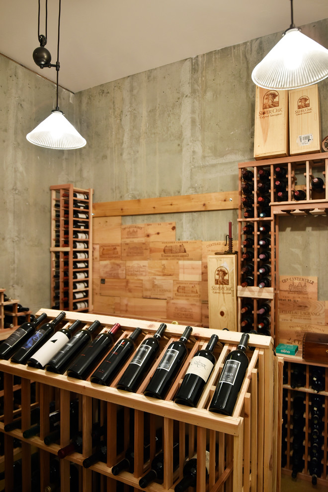 This is an example of a mid-sized contemporary wine cellar in Albuquerque with concrete floors and display racks.
