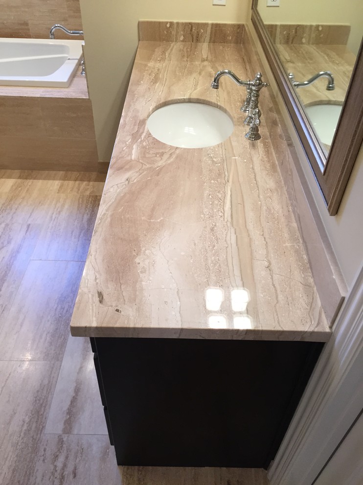 Inspiration for a large modern master bathroom in Dallas with an undermount sink, shaker cabinets, dark wood cabinets, marble benchtops, a drop-in tub, an alcove shower, a two-piece toilet, beige tile, stone tile, beige walls and travertine floors.