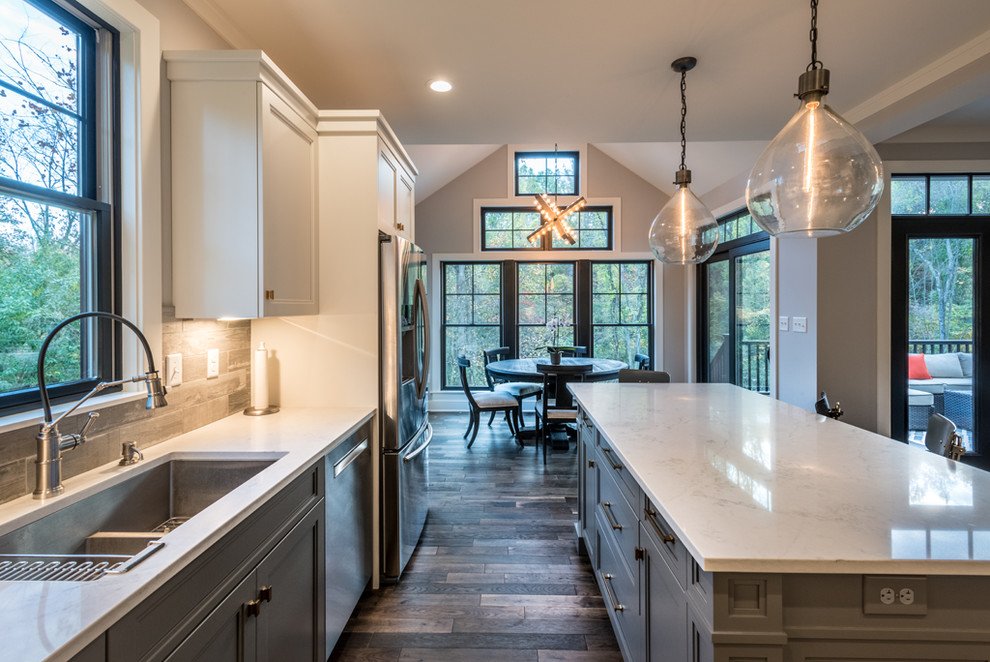 Photo of a country l-shaped eat-in kitchen in Other with beaded inset cabinets, white cabinets, quartz benchtops, grey splashback, ceramic splashback, stainless steel appliances, dark hardwood floors, with island and brown floor.