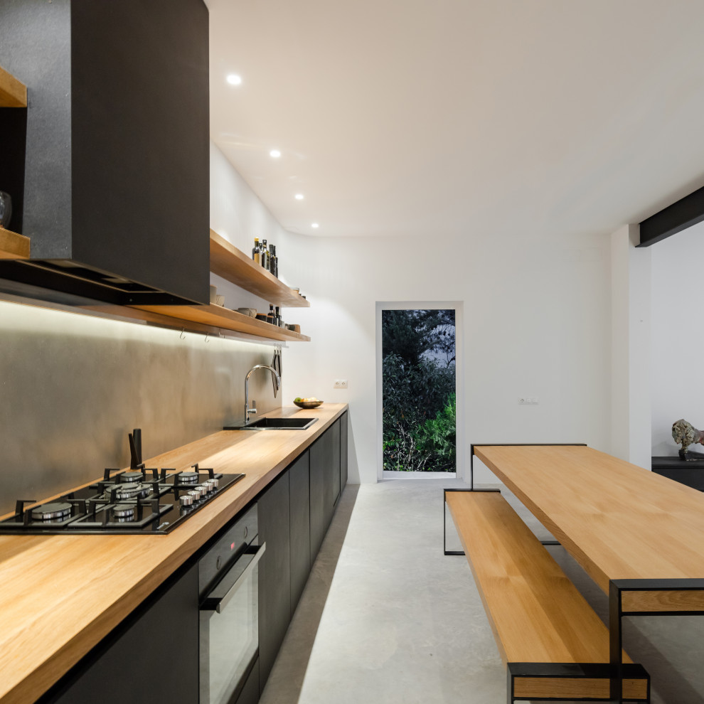 Design ideas for a large contemporary single-wall open plan kitchen in Valencia with flat-panel cabinets, black cabinets, wood benchtops, grey splashback, no island, grey floor, a drop-in sink, porcelain splashback, panelled appliances, porcelain floors and beige benchtop.