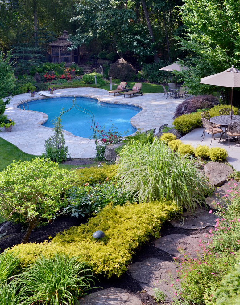 Design ideas for a large midcentury backyard custom-shaped natural pool in New York with natural stone pavers.