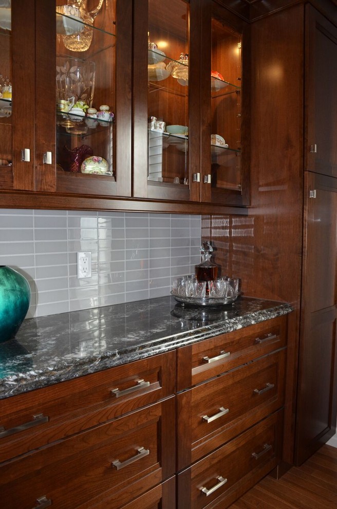 Large transitional l-shaped medium tone wood floor open concept kitchen photo in Toronto with an undermount sink, recessed-panel cabinets, dark wood cabinets, quartzite countertops, gray backsplash, glass tile backsplash, stainless steel appliances and an island