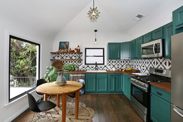 Photo of a mid-sized l-shaped eat-in kitchen in Los Angeles with a double-bowl sink, recessed-panel cabinets, green cabinets, wood benchtops, white splashback, ceramic splashback, stainless steel appliances, medium hardwood floors and no island.