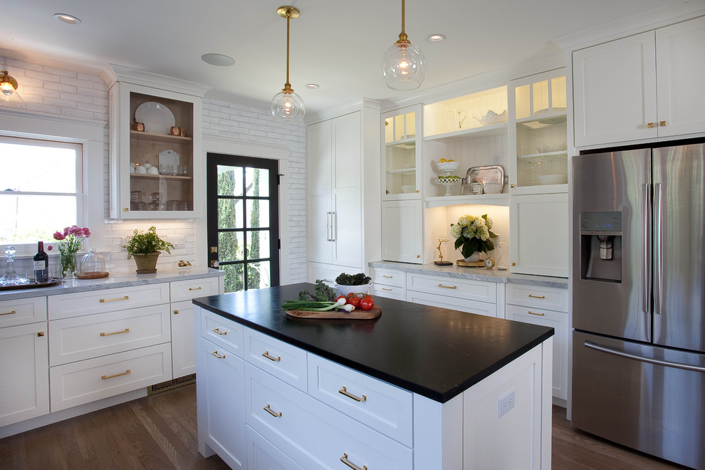 Example of a transitional u-shaped dark wood floor eat-in kitchen design in San Diego with a farmhouse sink, shaker cabinets, white cabinets, granite countertops, white backsplash, stainless steel appliances and an island