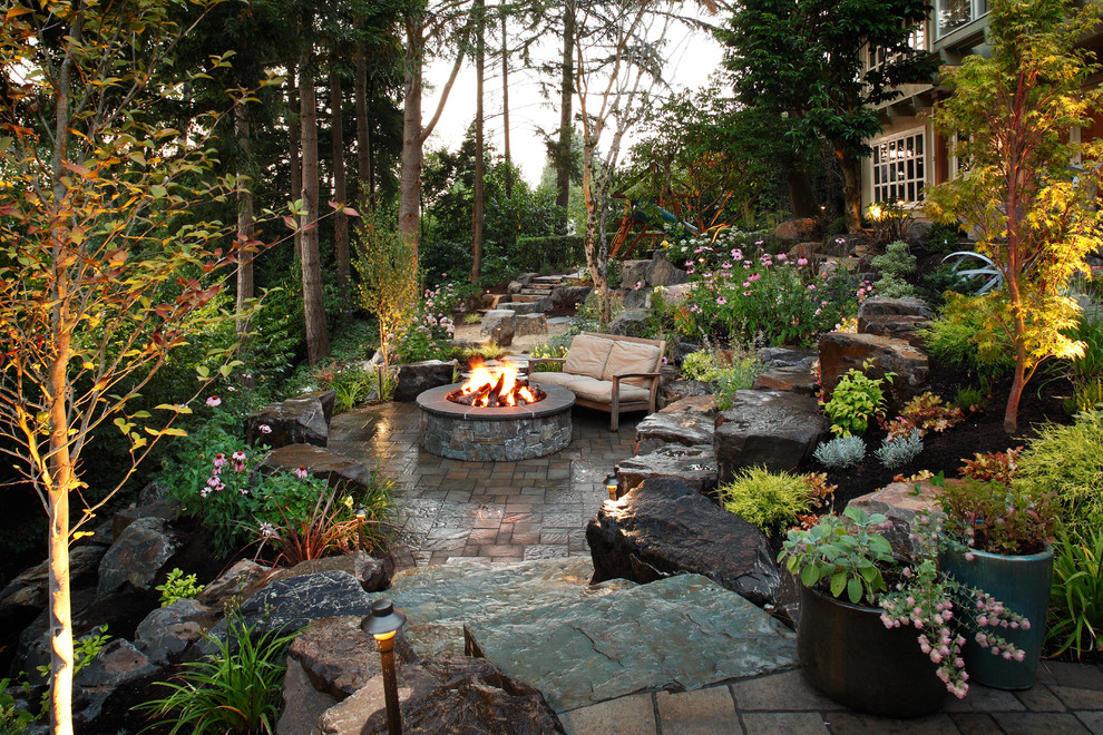 Large traditional backyard patio in Seattle with a fire feature and natural stone pavers.