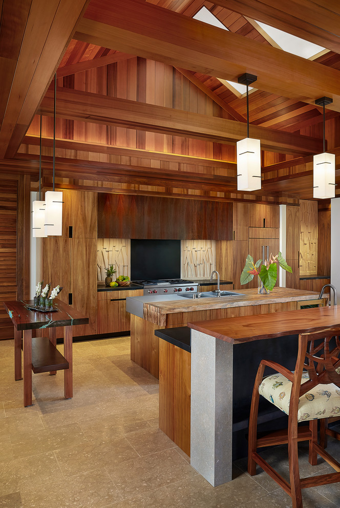 Photo of a large tropical galley open plan kitchen in Hawaii with an integrated sink, flat-panel cabinets, medium wood cabinets, wood benchtops, multi-coloured splashback, panelled appliances, limestone floors, multiple islands and limestone splashback.
