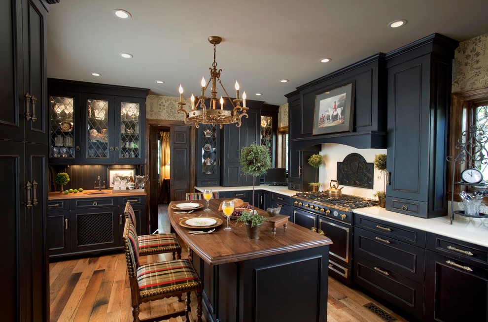 Traditional kitchen in New York with black cabinets, wood benchtops, beige splashback and black appliances.