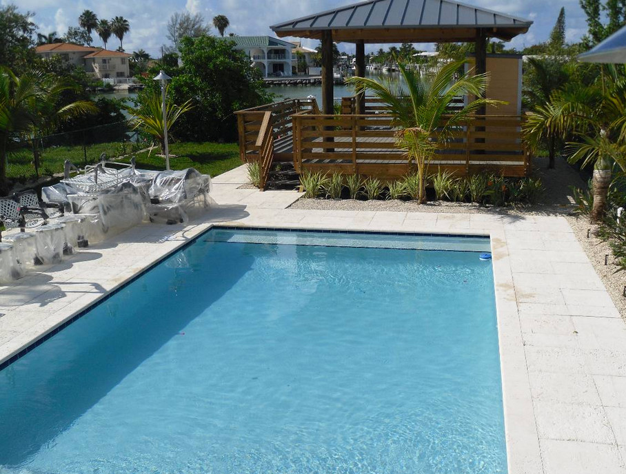 Example of a backyard tile and rectangular hot tub design in Miami