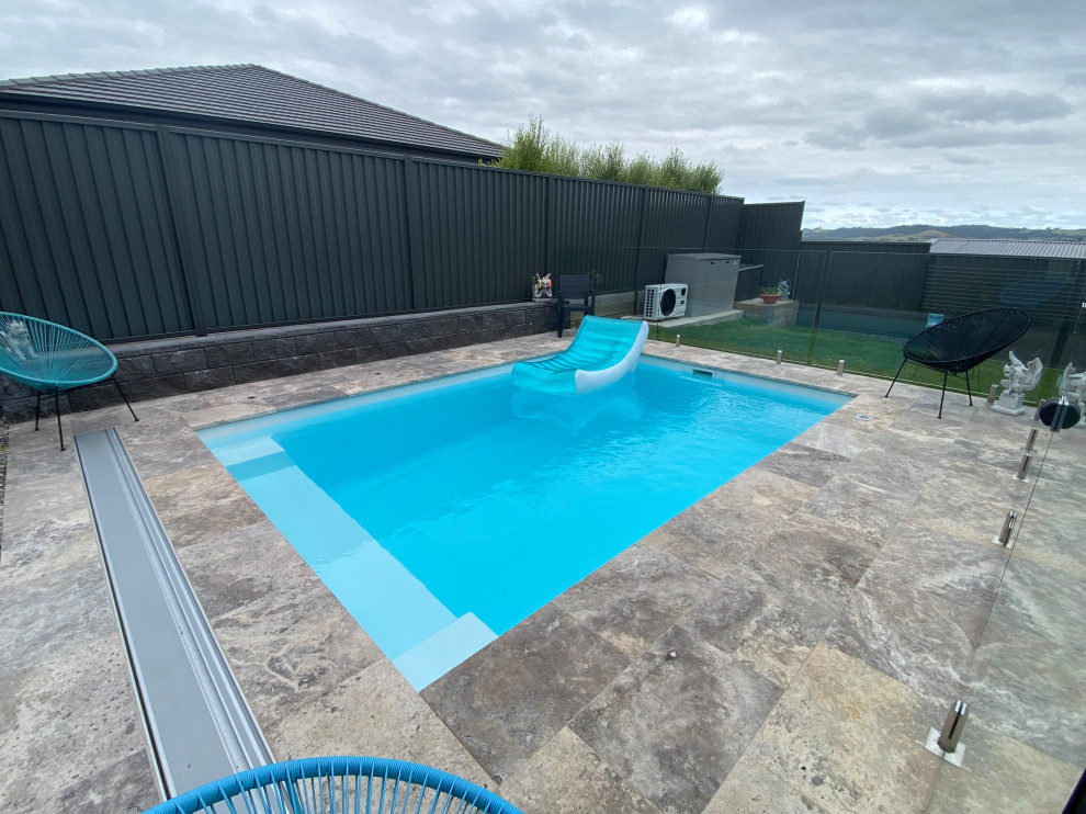 Foto di una piscina costiera rettangolare di medie dimensioni e dietro casa con pavimentazioni in pietra naturale