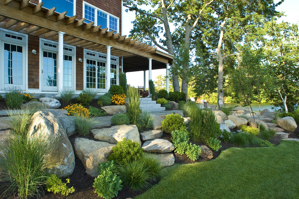 This is an example of a large beach style side yard full sun garden in Boston with natural stone pavers and with rock feature.