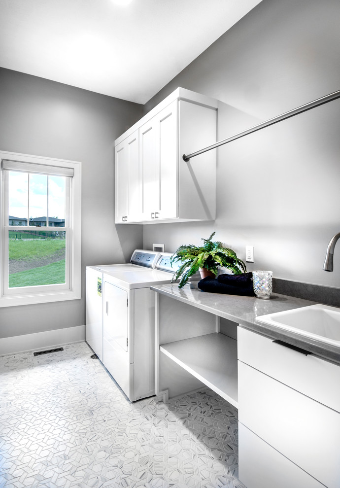 Design ideas for a large transitional utility room in Omaha with a drop-in sink, shaker cabinets, white cabinets, grey walls, marble floors, a side-by-side washer and dryer, white floor and grey benchtop.