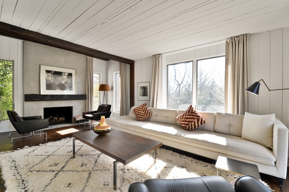 This is an example of a large contemporary formal open concept living room in New York with white walls, dark hardwood floors, a standard fireplace and a concrete fireplace surround.