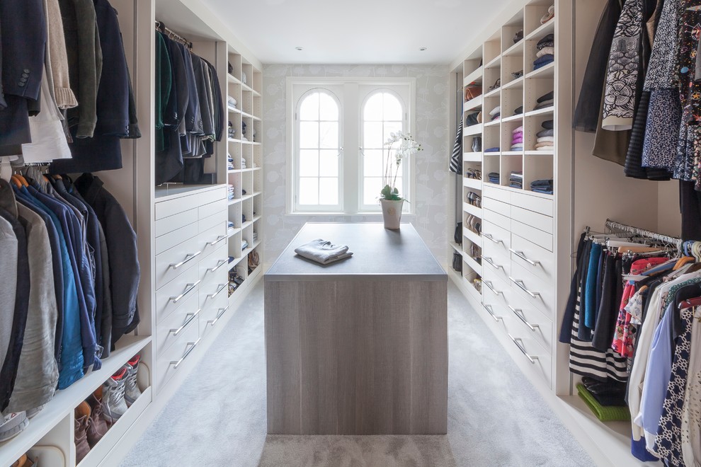 Photo of a transitional gender-neutral dressing room in London with flat-panel cabinets, white cabinets, carpet and grey floor.