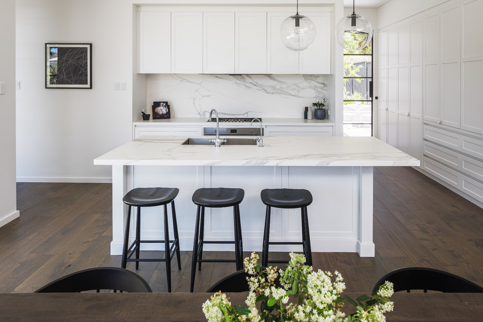 Inspiration for a contemporary l-shaped open plan kitchen in Perth with an undermount sink, shaker cabinets, white cabinets, quartz benchtops, white splashback, marble splashback, stainless steel appliances, dark hardwood floors, with island, white benchtop and brown floor.