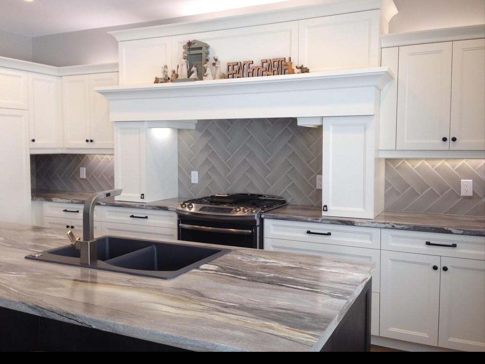 Example of a large transitional l-shaped medium tone wood floor and brown floor kitchen design with no island, a drop-in sink, recessed-panel cabinets, white cabinets, gray backsplash, porcelain backsplash and stainless steel appliances