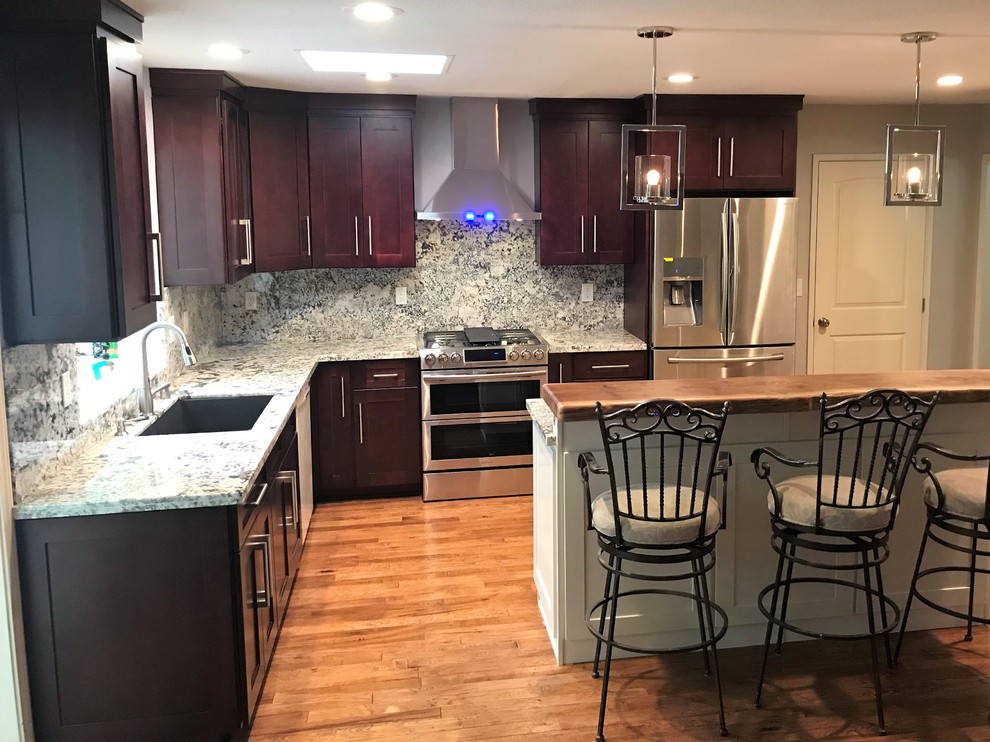 Example of a mid-sized transitional l-shaped light wood floor and brown floor eat-in kitchen design with an undermount sink, shaker cabinets, dark wood cabinets, granite countertops, multicolored backsplash, stone slab backsplash, stainless steel appliances, an island and multicolored countertops