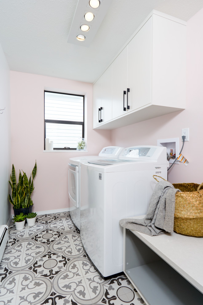This is an example of a small contemporary single-wall dedicated laundry room in Vancouver with flat-panel cabinets, white cabinets, quartz benchtops, pink walls, ceramic floors, a side-by-side washer and dryer, multi-coloured floor and grey benchtop.