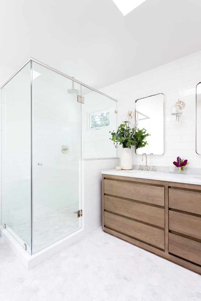 This is an example of a large modern master bathroom in New York with flat-panel cabinets, medium wood cabinets, a corner tub, an open shower, a one-piece toilet, white tile, stone tile, white walls, mosaic tile floors, a drop-in sink, solid surface benchtops, white floor and an open shower.