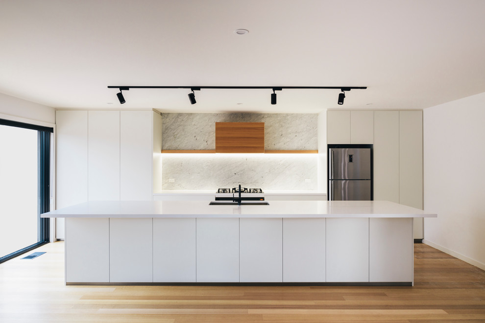 Design ideas for a mid-sized scandinavian galley kitchen in Canberra - Queanbeyan with an undermount sink, white cabinets, quartz benchtops, grey splashback, black appliances, medium hardwood floors and with island.