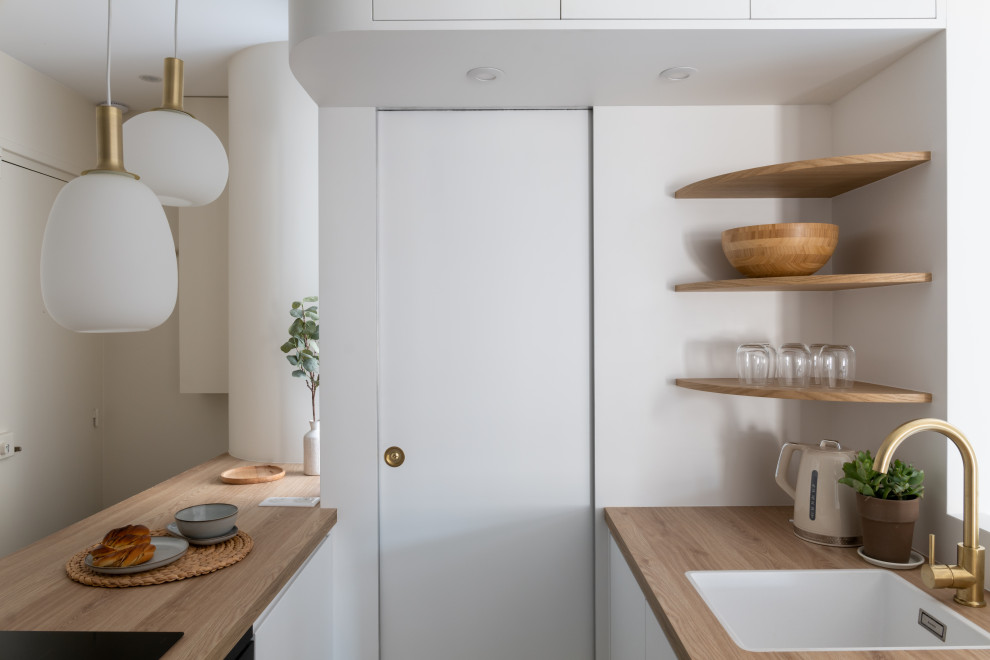 Ejemplo de cocina blanca y madera minimalista pequeña con fregadero de un seno, puertas de armario blancas, encimera de laminado, suelo de madera clara y suelo marrón