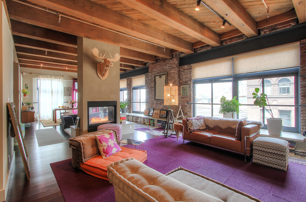 This is an example of a mid-sized industrial formal open concept living room in Seattle with beige walls, medium hardwood floors and a two-sided fireplace.