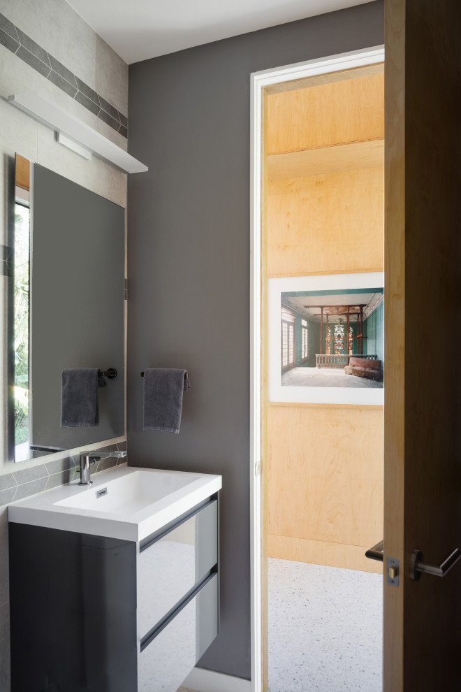 Bild på ett mellanstort funkis vit vitt badrum, med släta luckor, grå skåp, en kantlös dusch, en toalettstol med hel cisternkåpa, porslinskakel, betonggolv, ett integrerad handfat, bänkskiva i akrylsten, grått golv och med dusch som är öppen