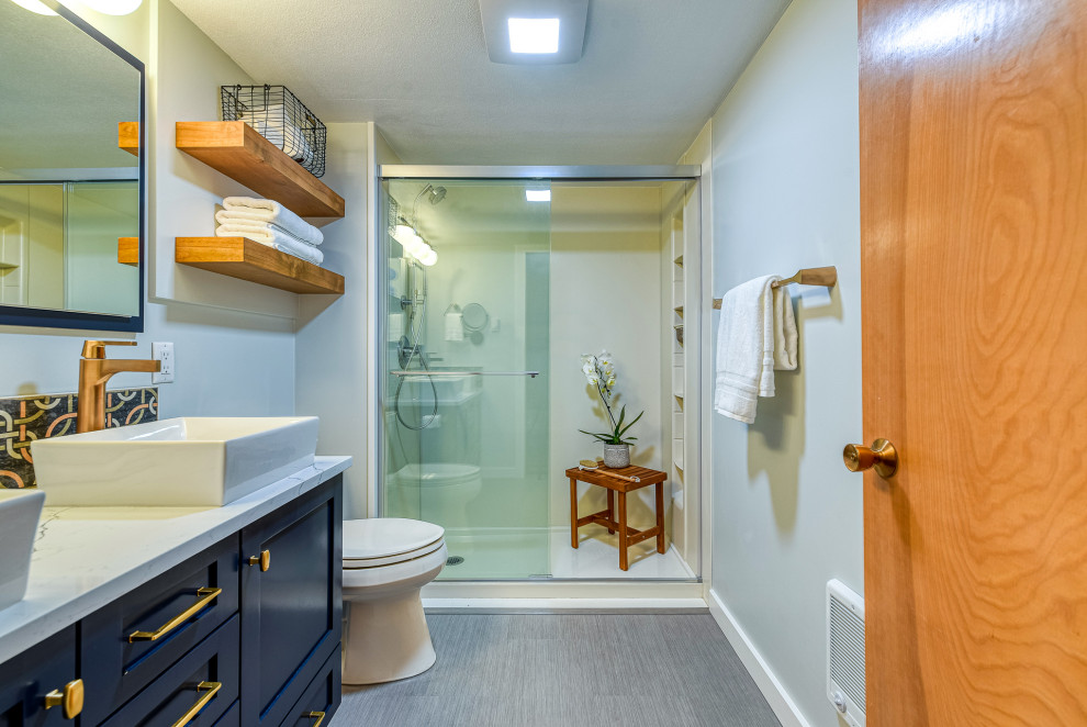 Свежая идея для дизайна: маленькая главная ванная комната в стиле неоклассика (современная классика) с фасадами в стиле шейкер, синими фасадами, душем, раздельным унитазом, серой плиткой, цементной плиткой, серыми стенами, полом из ламината, настольной раковиной, столешницей из кварцита, серым полом, душем с раздвижными дверями, белой столешницей, фартуком, тумбой под две раковины, встроенной тумбой, любым потолком и любой отделкой стен для на участке и в саду - отличное фото интерьера