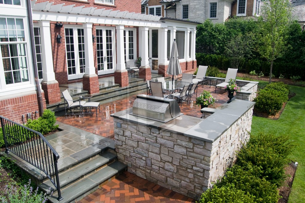This is an example of a mid-sized traditional backyard patio in Chicago with brick pavers and a pergola.