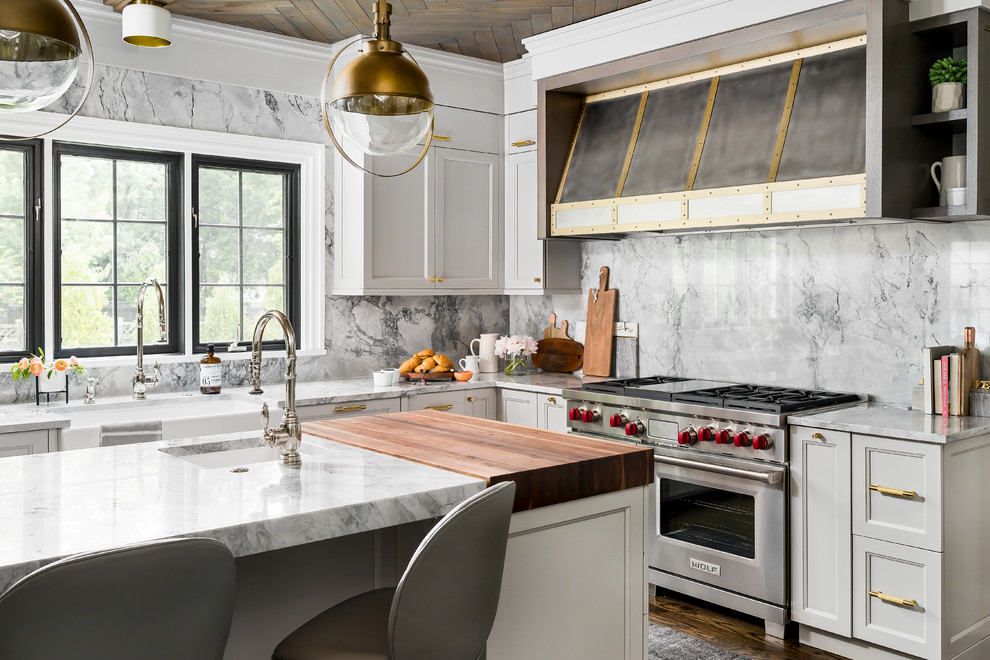 Inspiration for a mid-sized transitional l-shaped separate kitchen in Chicago with a farmhouse sink, recessed-panel cabinets, grey cabinets, quartzite benchtops, grey splashback, stone slab splashback, medium hardwood floors, with island, brown floor, grey benchtop and stainless steel appliances.