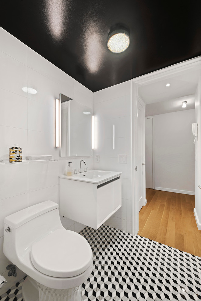 Inspiration for a small modern white tile marble floor powder room remodel in New York with a one-piece toilet, white walls, a wall-mount sink, flat-panel cabinets and white cabinets