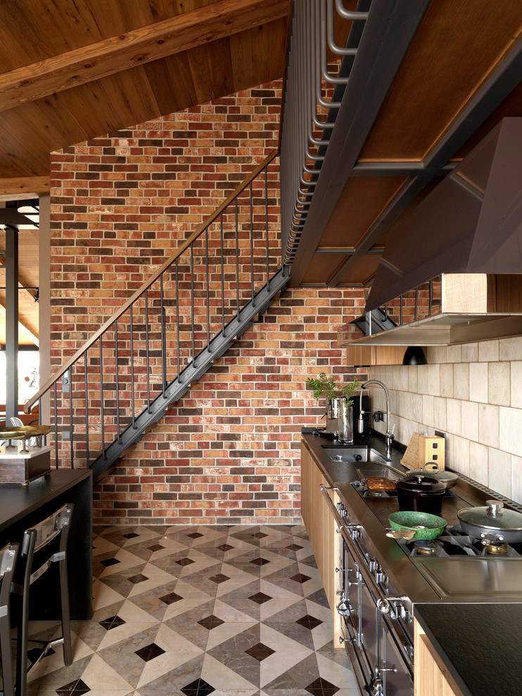 Inspiration for a mid-sized industrial single-wall eat-in kitchen in Moscow with marble floors, multi-coloured floor, an undermount sink, flat-panel cabinets, light wood cabinets, granite benchtops, beige splashback, ceramic splashback, black appliances and black benchtop.