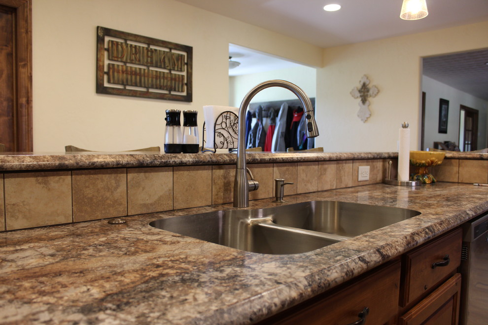 Inspiration for a large rustic l-shaped ceramic tile and beige floor open concept kitchen remodel in Denver with a drop-in sink, raised-panel cabinets, medium tone wood cabinets, laminate countertops, beige backsplash, ceramic backsplash, stainless steel appliances, an island and beige countertops