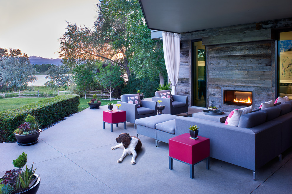 Inspiration for a contemporary backyard patio in Denver with concrete slab, a roof extension and with fireplace.