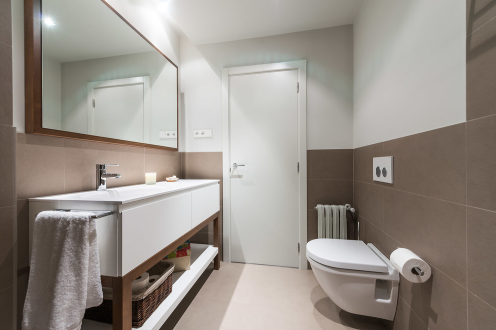 Imagen de aseo clásico renovado de tamaño medio con armarios con paneles lisos, puertas de armario blancas, sanitario de pared, paredes blancas y lavabo integrado