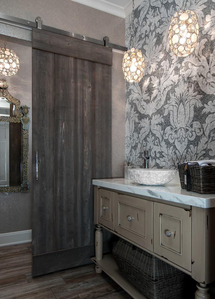 This is an example of a traditional powder room in Detroit with a vessel sink, furniture-like cabinets, grey walls, dark hardwood floors and distressed cabinets.