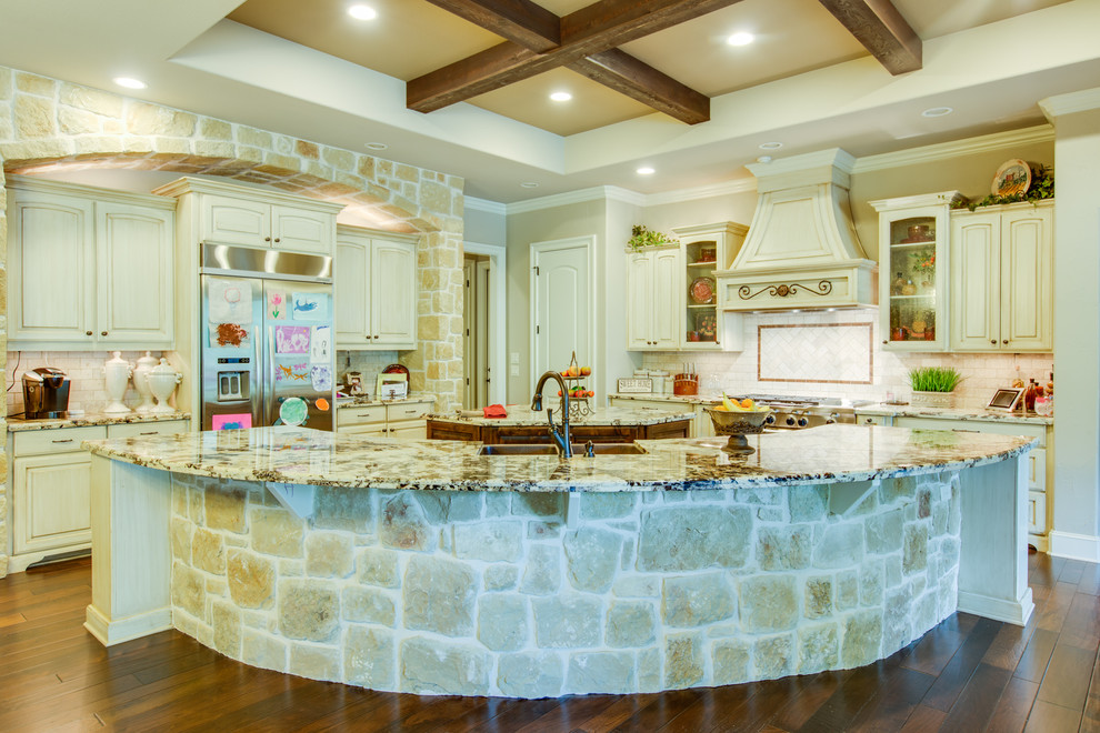 Photo of a large traditional kitchen in Austin with a double-bowl sink, raised-panel cabinets, white cabinets, glass benchtops, stone tile splashback, stainless steel appliances, dark hardwood floors and multiple islands.