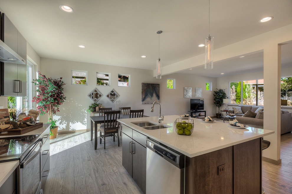 Inspiration for a large contemporary single-wall eat-in kitchen in Seattle with a double-bowl sink, flat-panel cabinets, brown cabinets, granite benchtops, white splashback, subway tile splashback, stainless steel appliances, light hardwood floors, with island and grey floor.