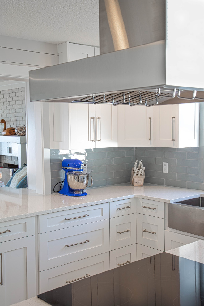 Photo of a large coastal single-wall kitchen/diner in Orlando with a submerged sink, shaker cabinets, white cabinets, engineered stone countertops, blue splashback, porcelain splashback, stainless steel appliances, porcelain flooring, an island, multi-coloured floors and white worktops.