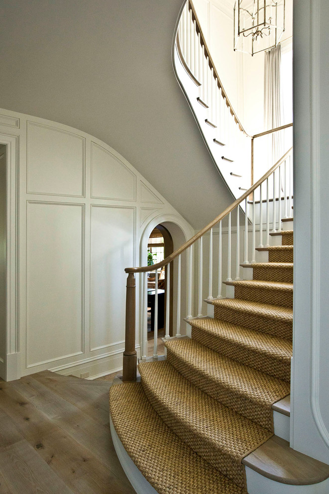 Large traditional wood u-shaped staircase in Charlotte with painted wood risers and wood railing.