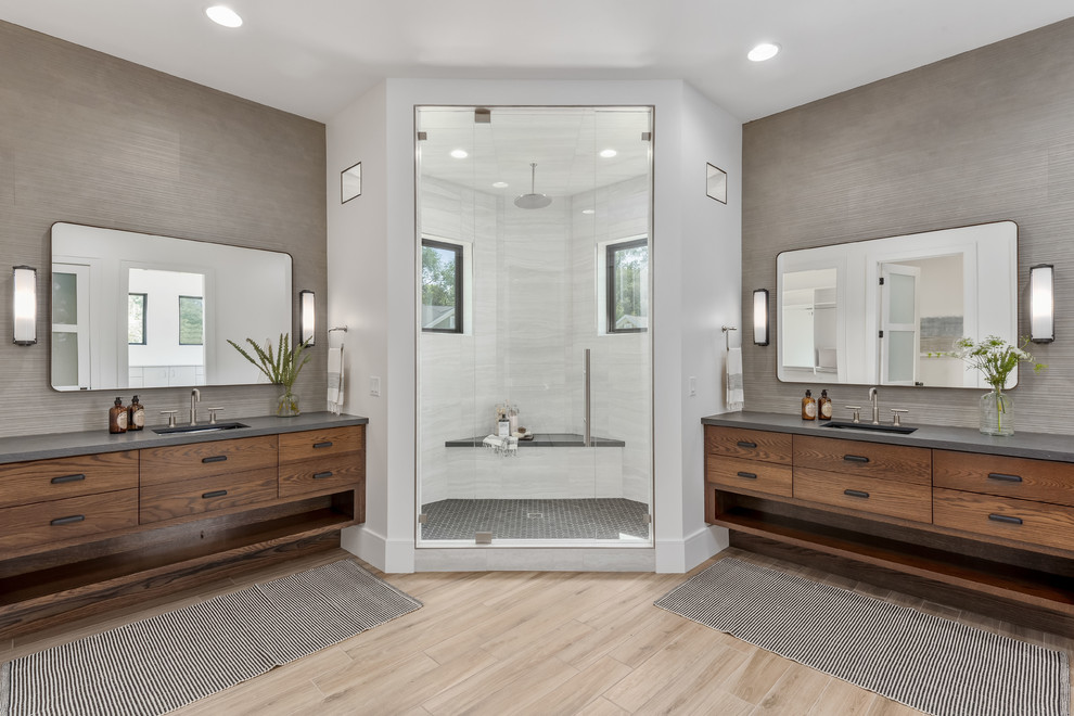 This is an example of a large contemporary master bathroom in Salt Lake City with flat-panel cabinets, medium wood cabinets, a corner shower, a one-piece toilet, gray tile, porcelain tile, white walls, porcelain floors, an undermount sink, quartzite benchtops, beige floor, a hinged shower door and grey benchtops.