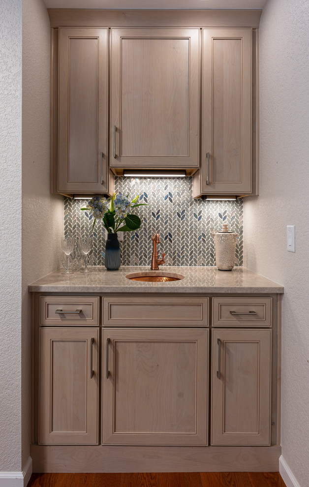 Photo of a small transitional single-wall wet bar in Denver with an undermount sink, flat-panel cabinets, light wood cabinets, quartzite benchtops, blue splashback, glass tile splashback, medium hardwood floors, brown floor and beige benchtop.
