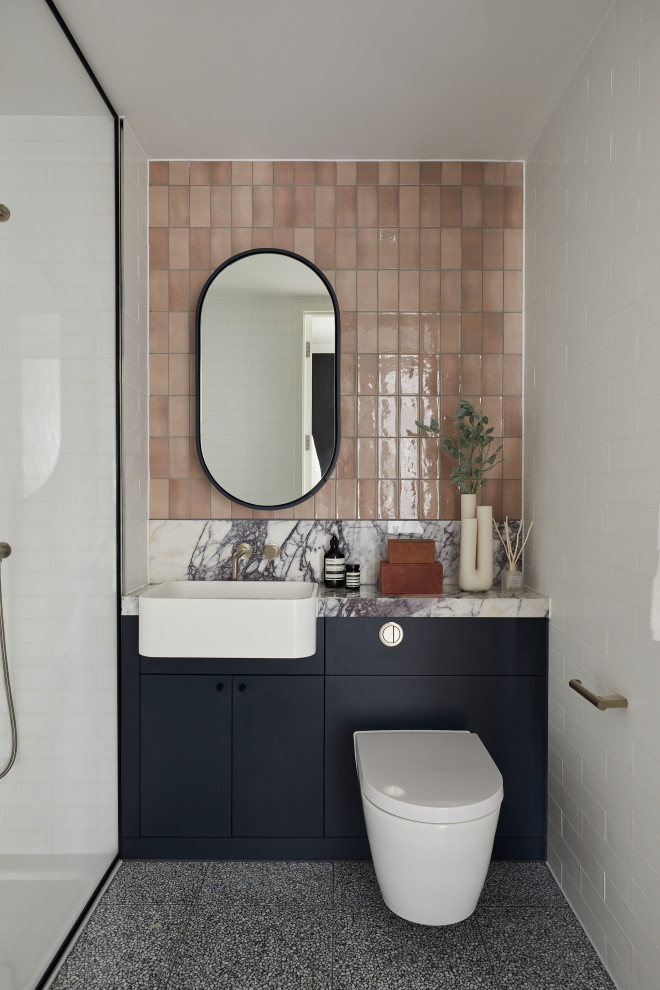 Идея дизайна: ванная комната в современном стиле с плоскими фасадами, черными фасадами, душем без бортиков, инсталляцией, розовой плиткой, накладной раковиной, серым полом, разноцветной столешницей, тумбой под одну раковину и встроенной тумбой